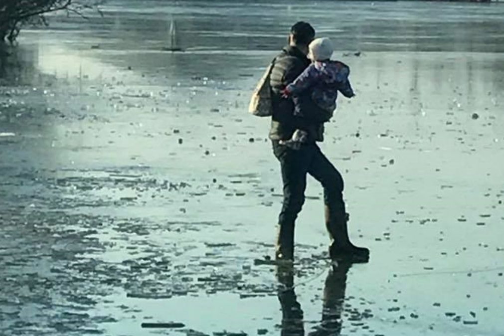 Homem atravessa lago congelado com bebé ao colo