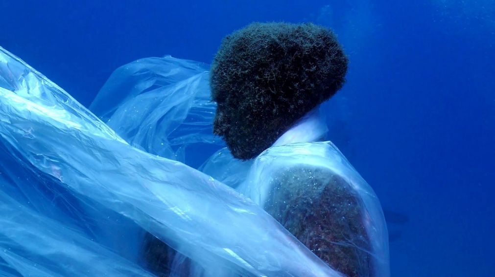 Mergulhadores envolvem esculturas humanas de museu submerso com plástico