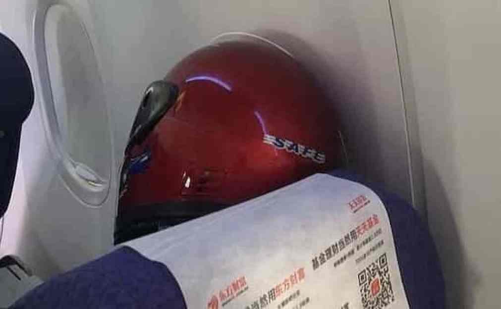 Homem usa capacete durante voo para se proteger do coronavírus