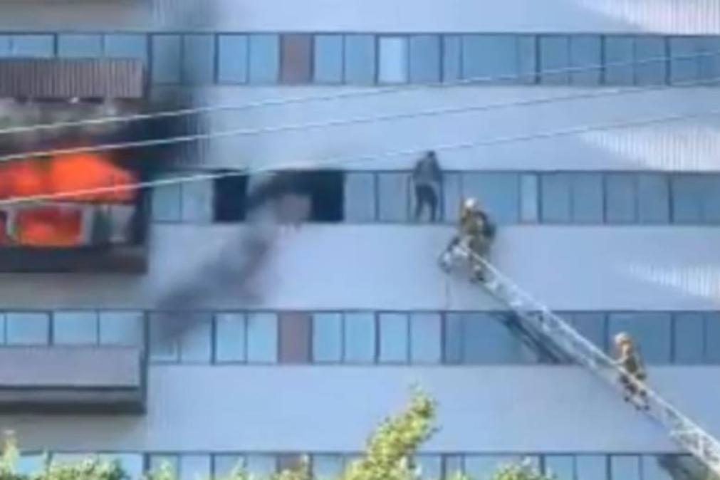 Incêndio em prédio de 25 andares leva homem a pendurar-se para escapar às chamas [vídeo]